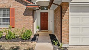 Une maison d’habitation avec une façade en briques, une porte d’entrée et un garage.