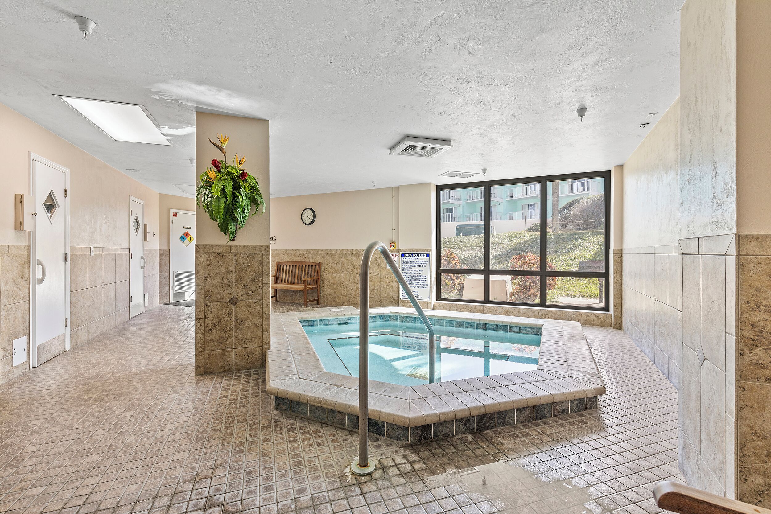 Un hall d’hôtel doté d’une piscine, d’une horloge et d’une grande fenêtre donnant sur l’extérieur.