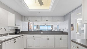 A modern kitchen with white cabinets, a large island, and a skylight. - ☀️ Ocean Front - Sherwin Condominium 1702 ☀️ (Daytona Beach Shores)