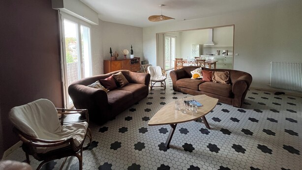 Un salon comprenant deux canapés, une table basse et un coin repas avec des chaises et une table.
