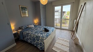 Une chambre avec un lit, des lampes de chevet, un luminaire suspendu, une fenêtre donnant sur un paysage agréable et une échelle en bois appuyée contre le mur.