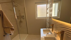 Une salle de bain moderne avec une douche à parois de verre, un grand miroir et un meuble-lavabo.