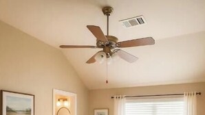 Una habitació amb un llit, un ventilador de sostre, una finestra amb persianes, una taula petita amb una cadira i un armari.