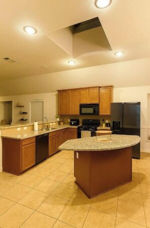 A modern kitchen with wooden cabinets, a central island, and built-in appliances.