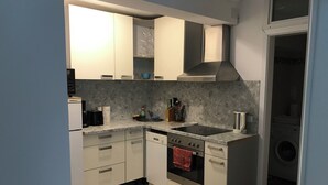 A modern kitchen with white cabinets, a built-in oven, a sink, and a stove. - 2 bedrooms in Breuberg Odenwald (Breuberg)