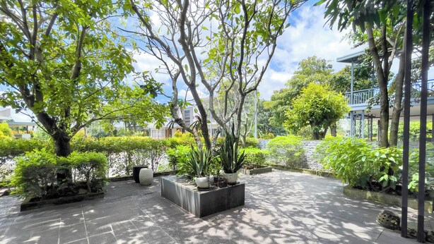 A courtyard with a tiled floor, potted plants, and trees. - Lumiere Villa Swanbay  (Nhon Trach)