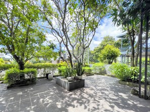 A courtyard with a tiled floor, potted plants, and trees. - Lumiere Villa Swanbay  (Nhon Trach)
