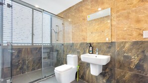 A modern bathroom with a glass shower enclosure, a toilet, and a sink with a soap dispenser. - Lumiere Villa Swanbay  (Nhon Trach)