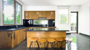 A modern kitchen with a central island, bar stools, and large windows. - Lumiere Villa Swanbay  (Nhon Trach)