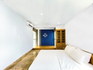 A modern hotel room with a large bed, a wardrobe, and a blue accent wall with motivational text. - Lumiere Villa Swanbay  (Nhon Trach)
