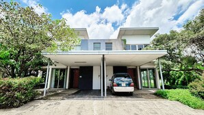 A modern two-story house with a covered driveway and a car parked inside. - Lumiere Villa Swanbay  (Nhon Trach)