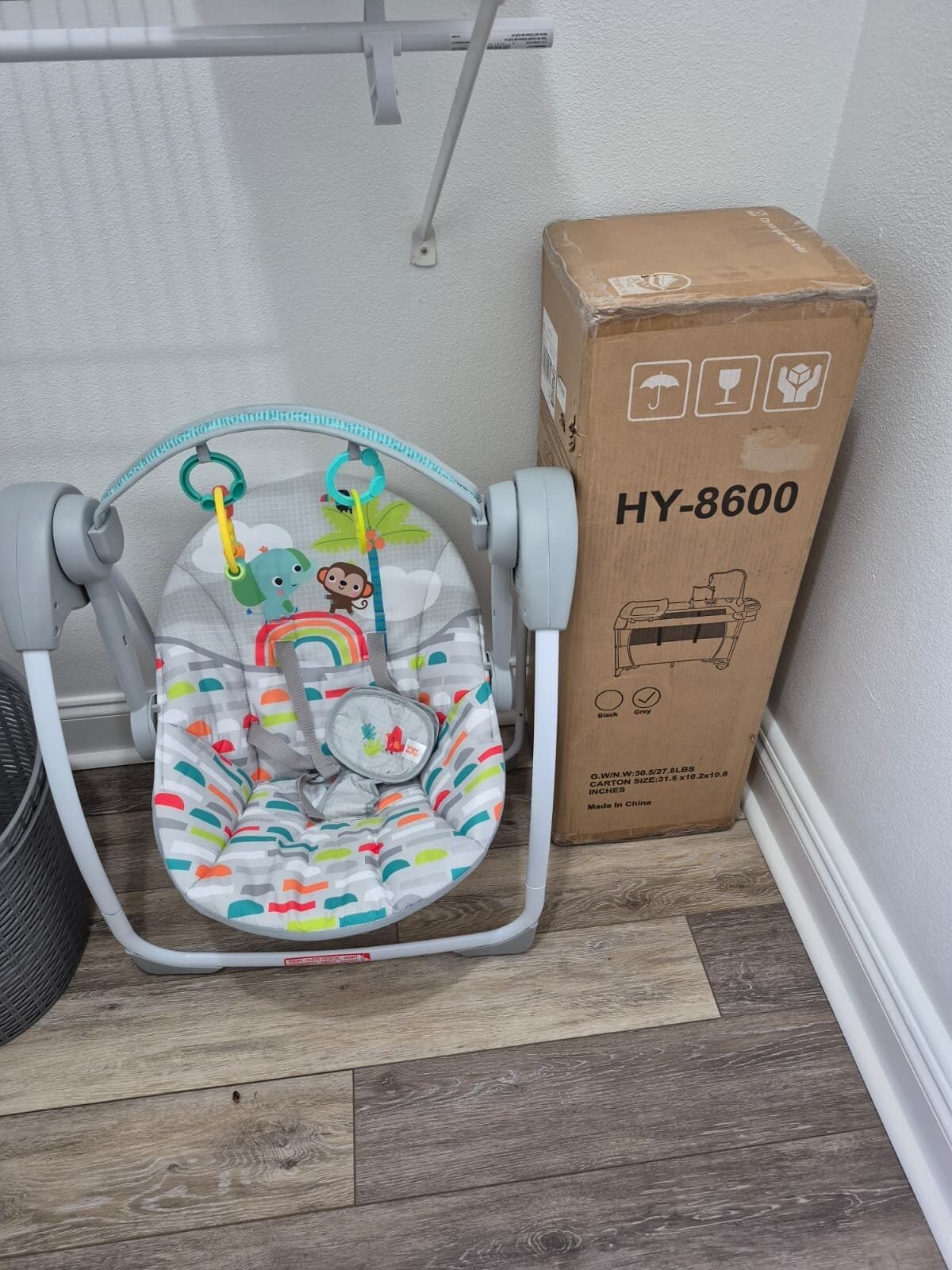 Een babyzitje met kleurrijke patronen en een hangend speeltje, naast een kartonnen doos met de tekst HY-8600.