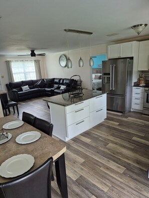 Una cocina moderna con una isla central, armarios blancos y un refrigerador de acero inoxidable.