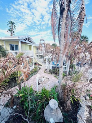 A residential area with a pathway, palm trees, and a house with a white fence. - Penguins on the Beach Villas (Cocoa Beach)
