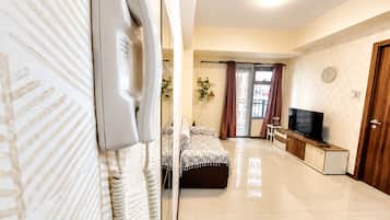 A hotel room with a bed, a television, a desk, and a door.