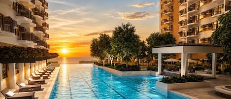 Ein Schwimmbecken mit Liegestühlen und Blick auf den Sonnenuntergang.