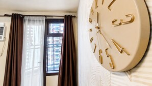 A room with a large wall-mounted clock, a window with curtains, and an air conditioning unit. - Levi & Moon Relax and Chill (Pasay)