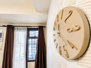 Una stanza con un orologio da parete grande, una finestra con tende e un condizionatore.