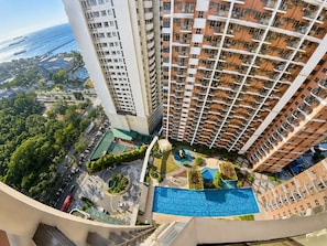 A high-rise building with multiple balconies, a rooftop pool, and a view of the sea. - Levi & Moon Relax and Chill (Pasay)