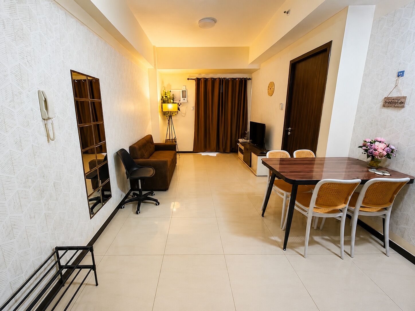 A compact living space with a dining area, a sofa, a TV, and a lamp.