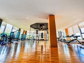 A gym with exercise equipment, large windows, and a wooden floor. - Levi & Moon Relax and Chill (Pasay)