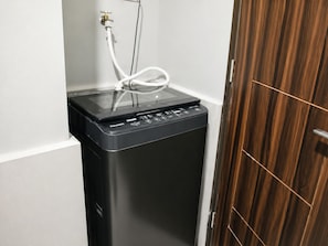 A compact, black portable washer-dryer unit with a control panel, connected to a power outlet and a water hose. - Levi & Moon Relax and Chill (Pasay)