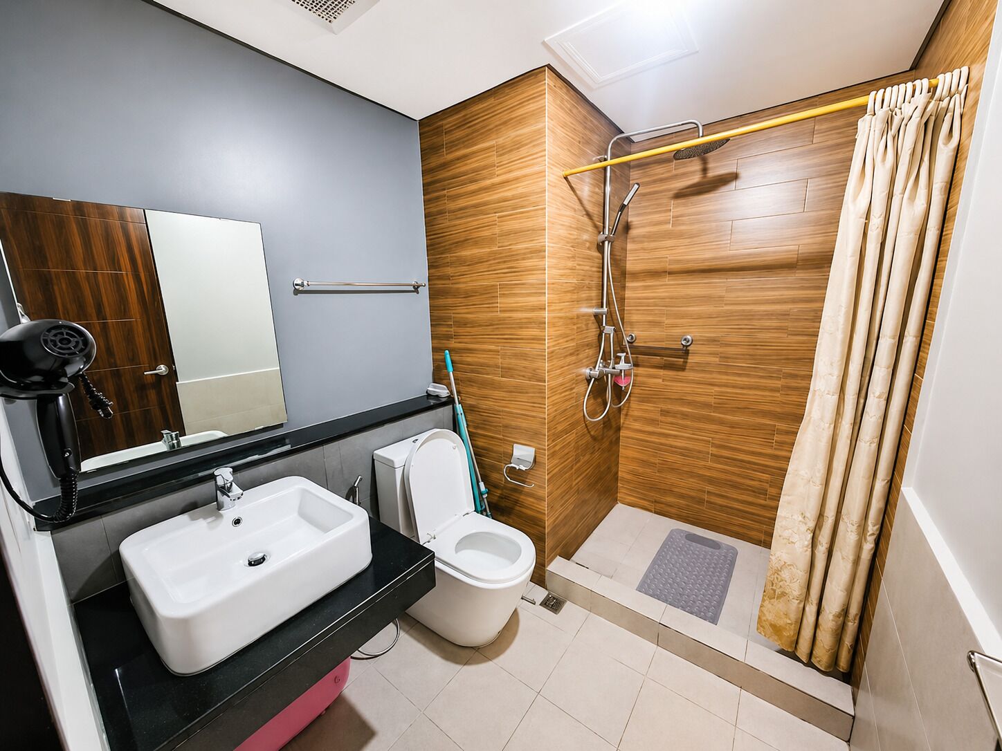 Een moderne badkamer met een douchecabine van hout, een witte wastafel en een toilet.
