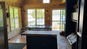 A wooden cabin with a kitchen area, large windows, and a view of the outdoors. - Charming 2-bedroom cabin in Portage Lake (Portage Lake)