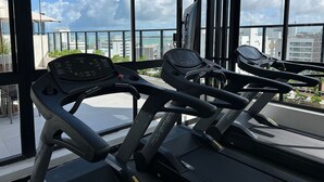 Et fitnesscenter med løbebånd og udsigt over byen gennem store vinduer.