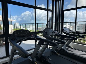 Ein Fitnessstudio mit Laufbändern und Blick auf die Stadt durch große Fenster.