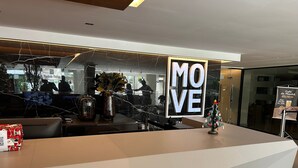 En receptionsdisk med et skilt, der siger 'MOVE', et lille juletræ og en plakat med teksten 'Cafe da Manhã'.
