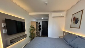 Et moderne hotelværelse med en stor seng, et fladskærms-TV på væggen, en potteplante og en aircondition.