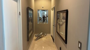 A hallway with a glass display case containing trophies, a silver sculpture, and a framed picture on the wall.