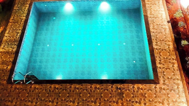 Une piscine avec un bord carrelé et un escalier en métal.