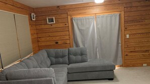 Ein Zimmer mit einer Eckcouch, einem kleinen Tisch und einem Sessel.