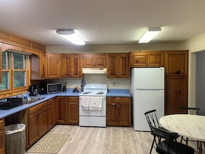Una cucina con mobili in legno, piano cottura bianco, forno a microonde e frigorifero.