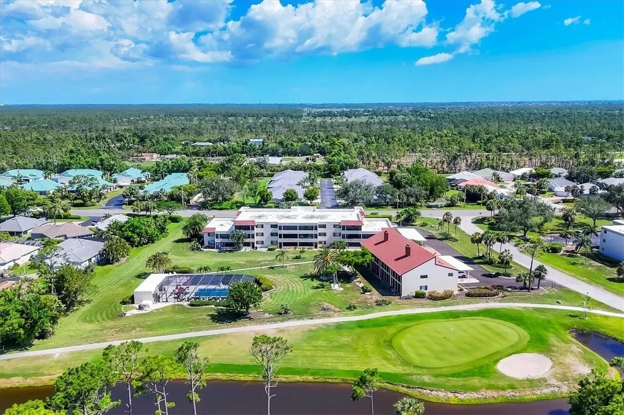 Ein Luftbild eines Wohngebiets mit Häusern, einem großen Gebäude mit rotem Dach und einem Golfplatz.