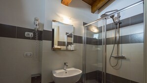 A modern bathroom with a glass-enclosed shower, a white sink, and a mirror above it. - Hotel Centova (Perugia)