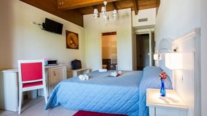 A bedroom with a bed, bedside table, lamp, TV, and a red chair. - Hotel Centova (Perugia)
