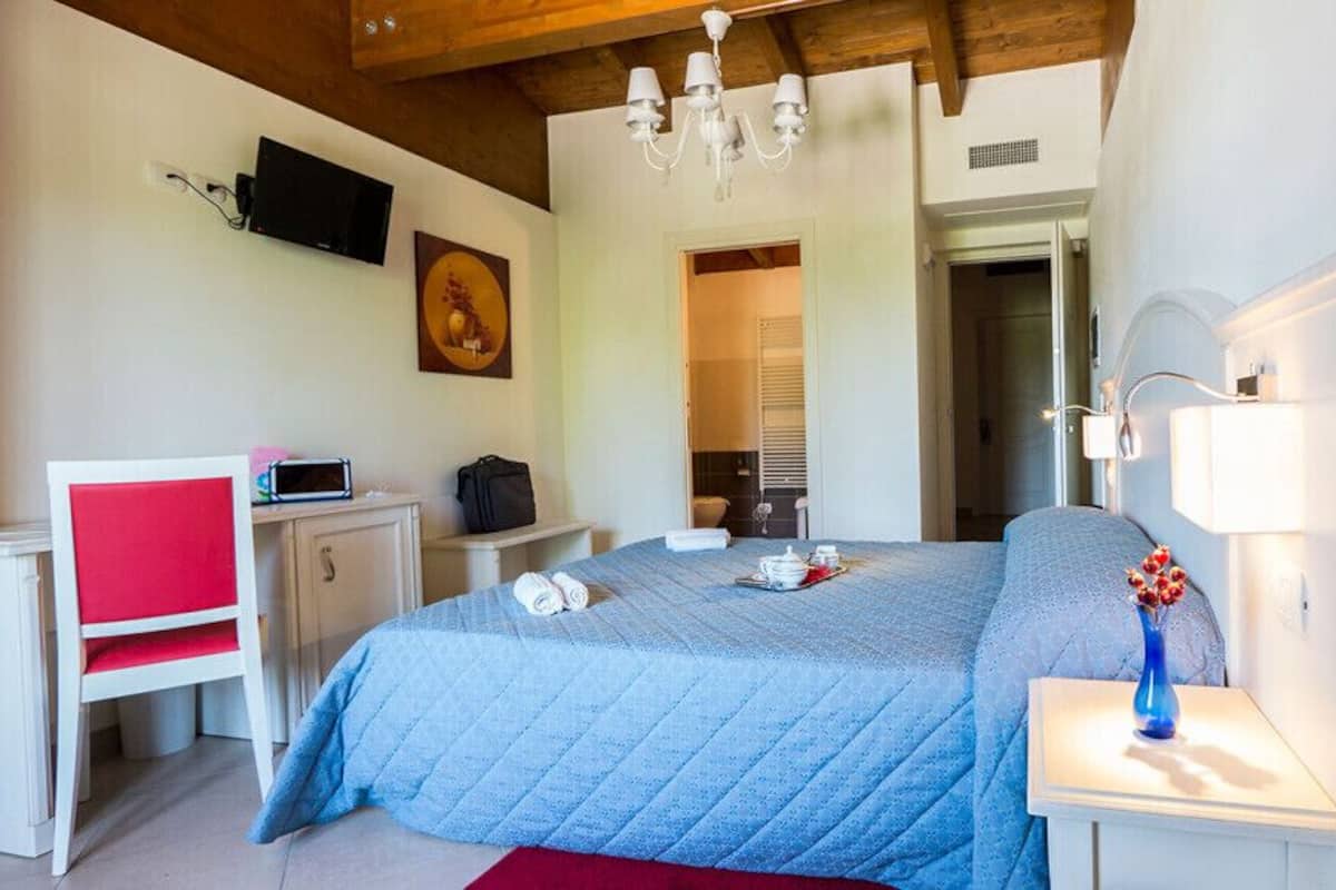 A bedroom with a bed, bedside table, lamp, TV, and a red chair.