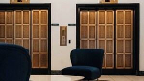 A hotel lobby with two elevators, a reception desk, and a blue armchair. - The Lofty Loft - True City Living in Downtown Denver (Denver)
