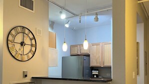 A compact kitchen with a built-in refrigerator, wooden cabinets, and two stools. - The Lofty Loft - True City Living in Downtown Denver (Denver)