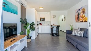 Una sala de estar moderna con televisor, comedor y cocina.