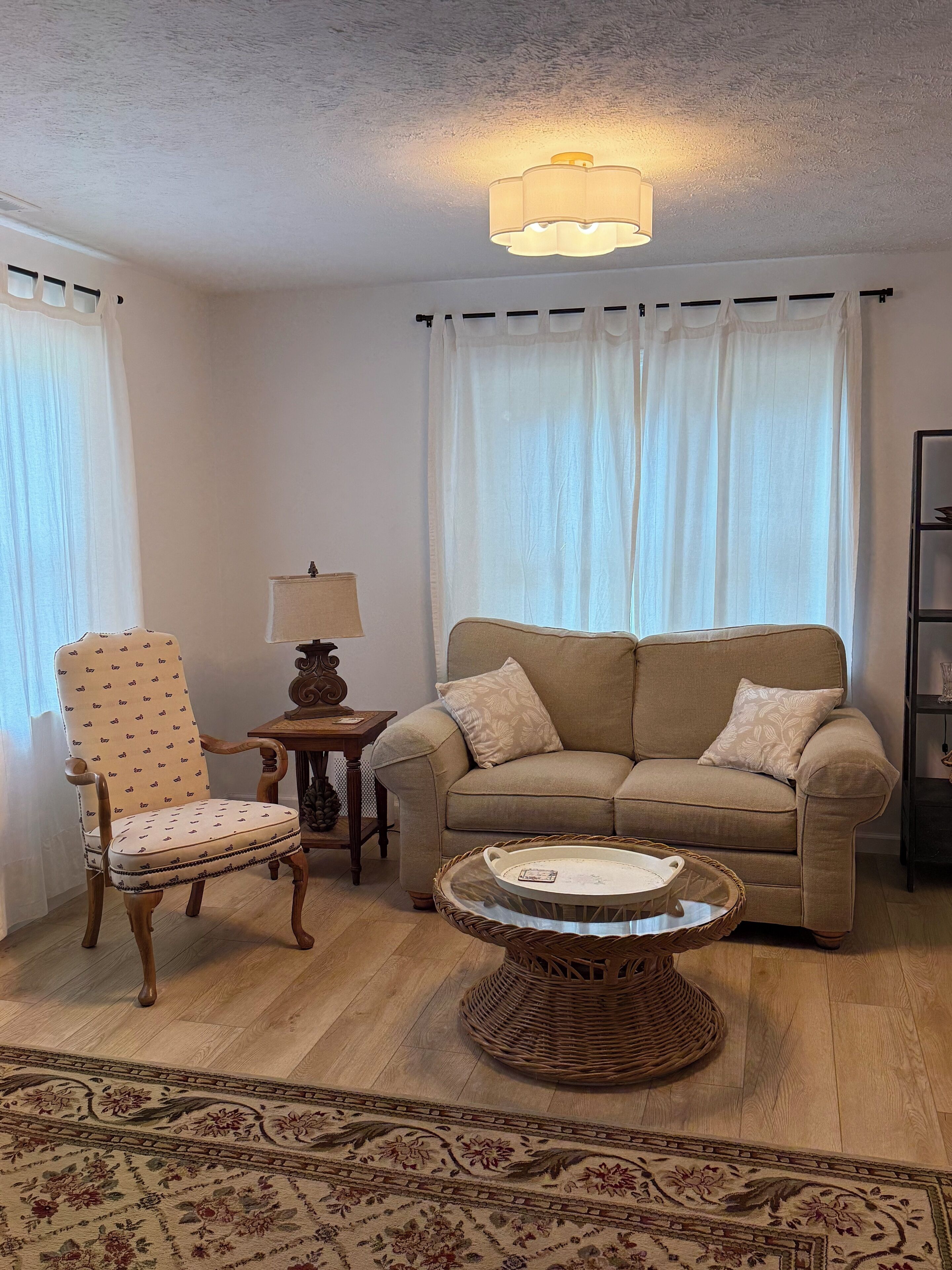 Ein Wohnzimmer mit einer Couch, einem Sessel und einem kleinen Tisch mit einer Lampe.
