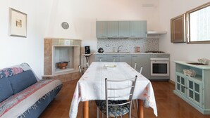 Une cuisine de taille réduite comprenant une table à manger, des chaises, un canapé et un petit meuble.