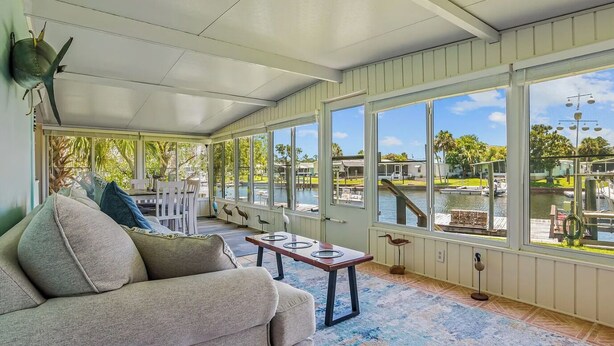 A sunroom with a view of a water body, a sofa, and a small table.