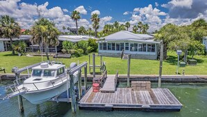 A marina with a docked boat, a covered structure, and lush greenery.