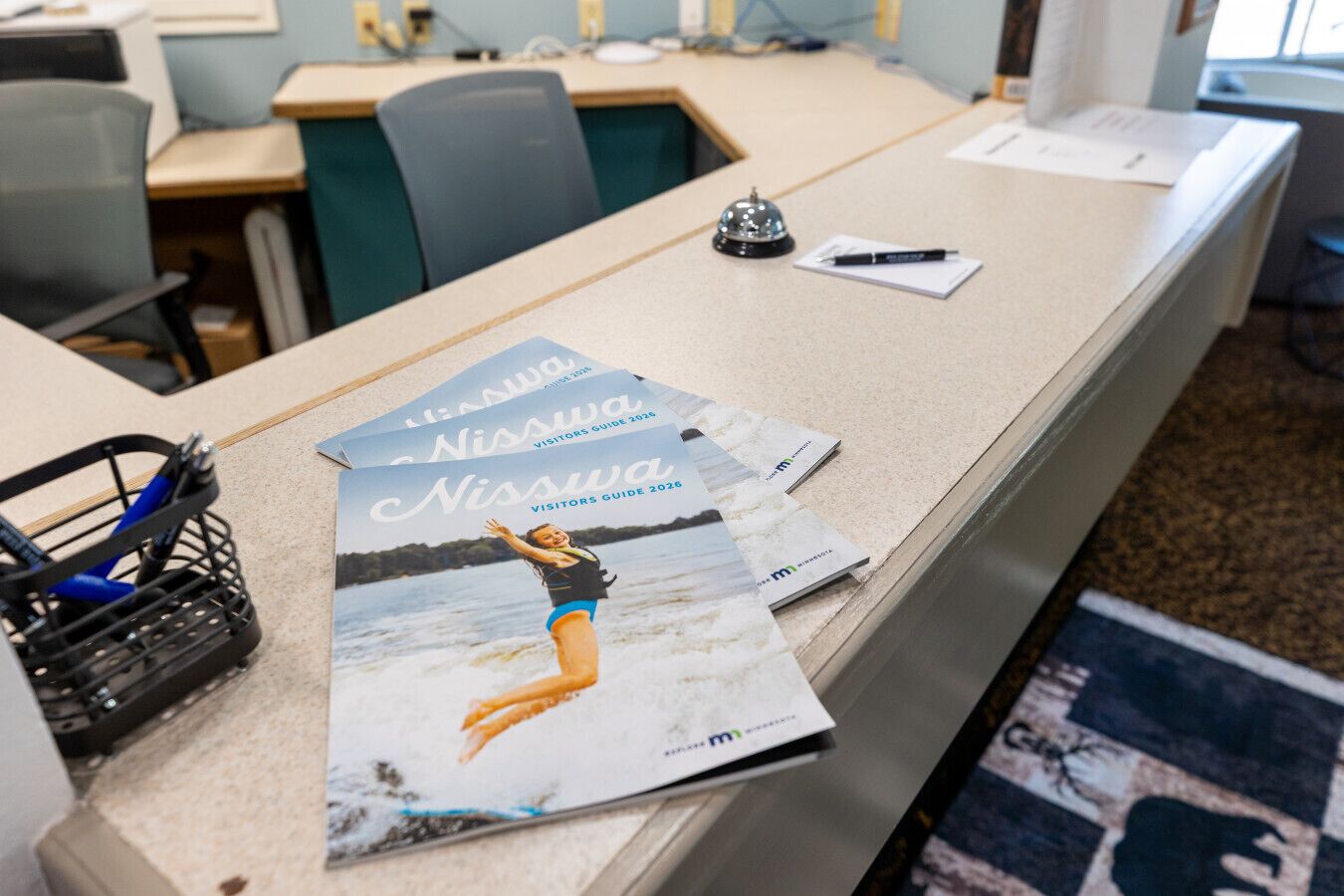 Un comptoir d’accueil avec des brochures, un stylo et une clochette.