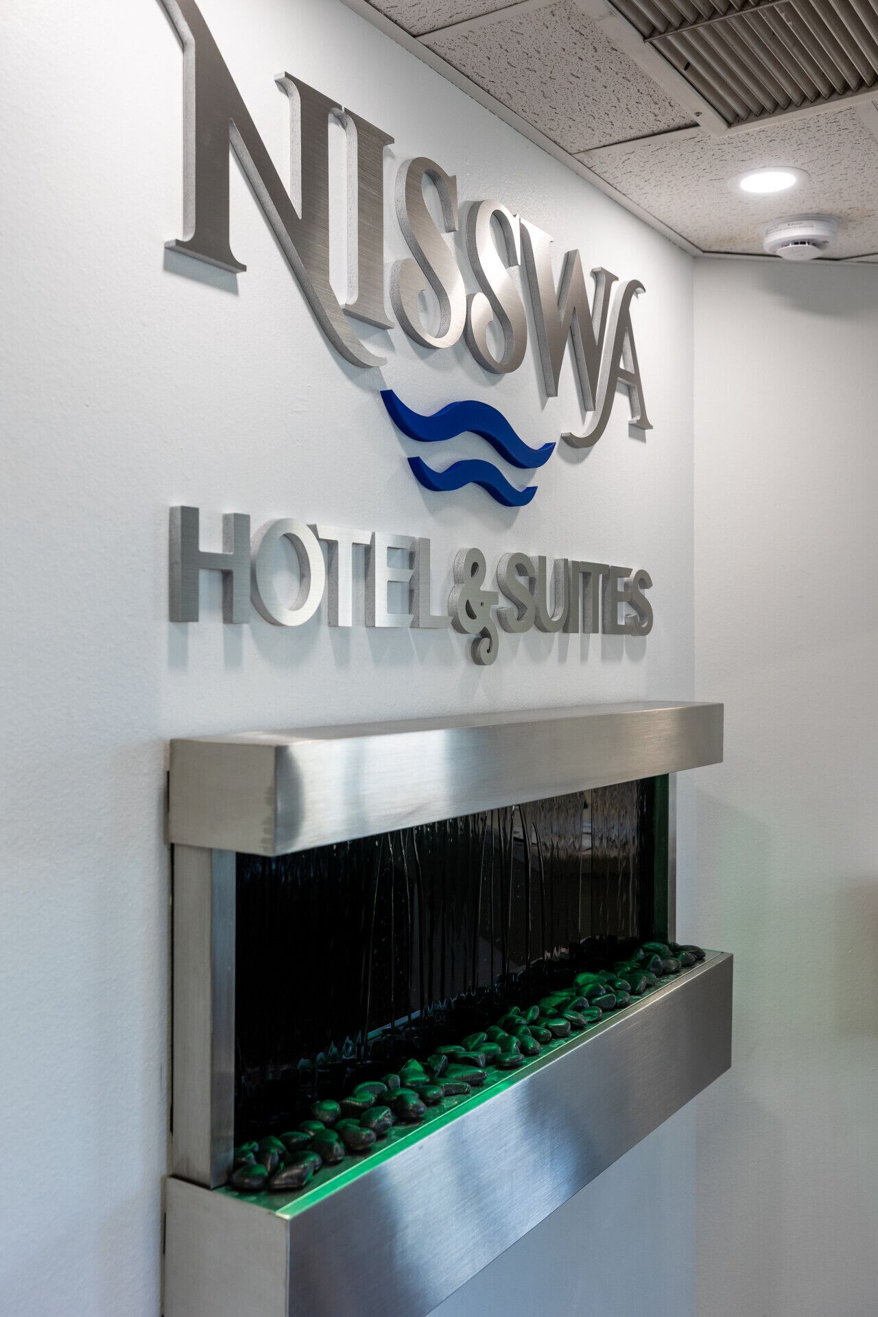 A hotel sign with the name 'Nisswa Hotel & Suites' and a water feature below it.