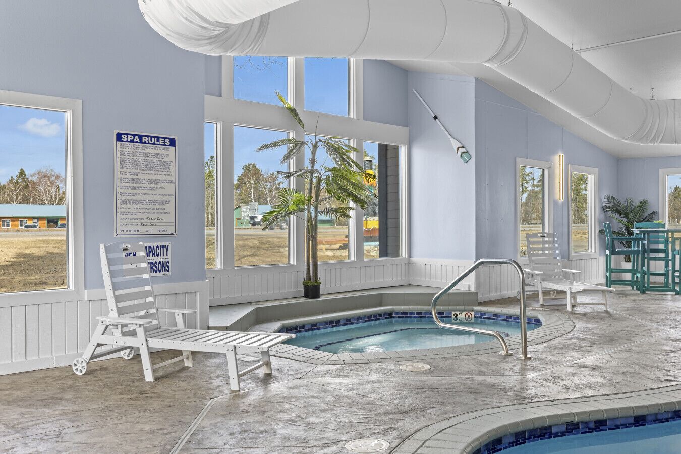 Un spa con piscina, sillas blancas y amplios ventanales.